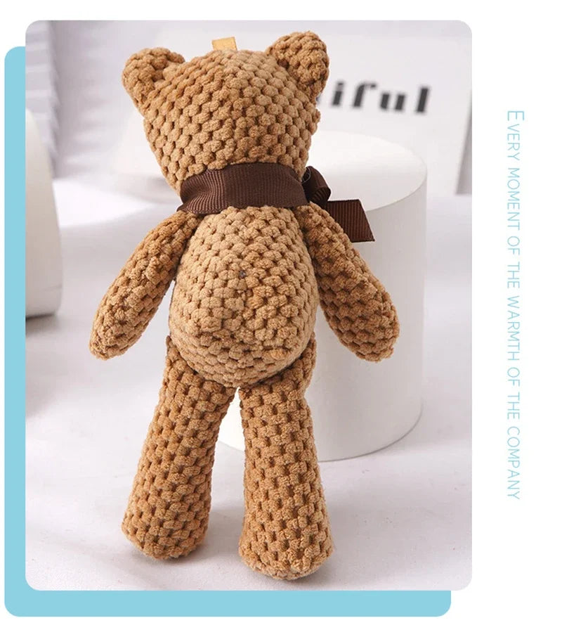 A handcrafted, textured brown stuffed bear key pendant with a dark brown ribbon around its neck.