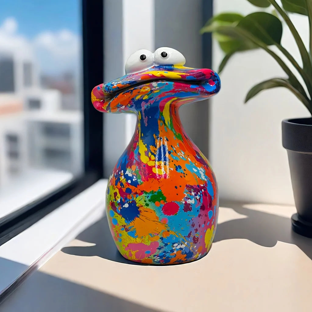 A colorful resin figurine shaped like a frog with large eyes sitting on a windowsill.