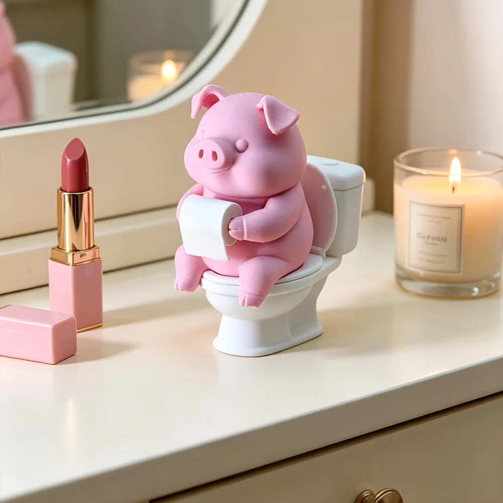 Figurine de porc en céramique rose assise sur une cuvette blanche, à côté d'un rouge à lèvres doré et d'une bougie.