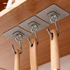 Silver adhesive wall hooks hanging from a wooden shelf for home organization