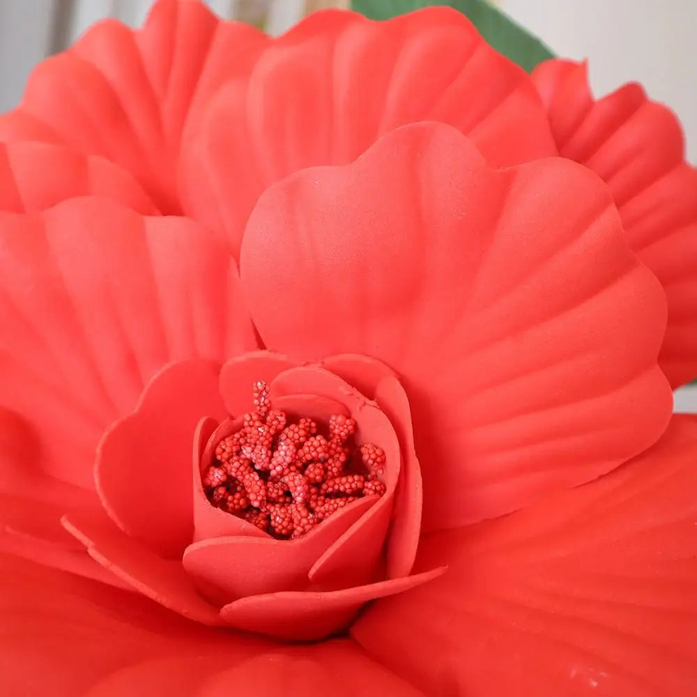 A close-up of a vibrant red artificial peony flower with tiny red beads in the center.