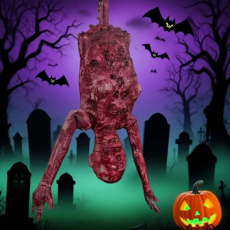 A realistic, reddish-brown hanging corpse prop with elongated limbs is displayed in a graveyard setting.
