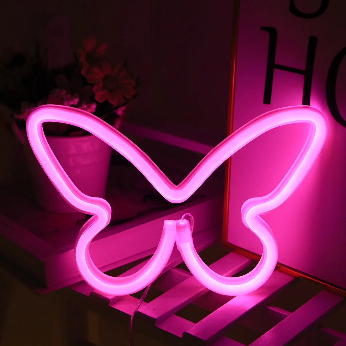 A pink neon sign shaped like a butterfly is displayed on a wooden surface.