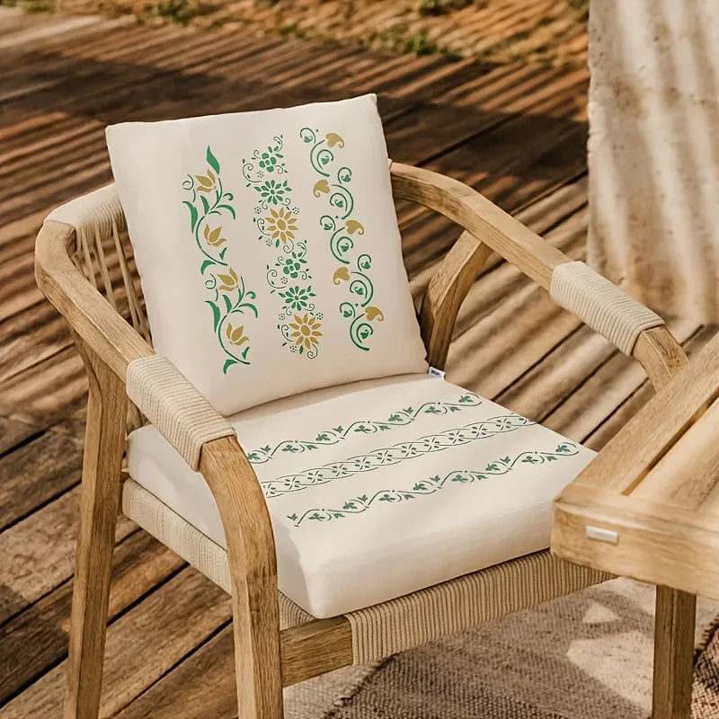 A light cream cushion with green floral alphabet stencils rests on a wooden chair.