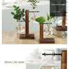 A set of wooden plant vases with glass globes holding fresh greenery and herbs.