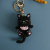 A handcrafted crochet black cat pendant keychain with a gold-colored ring attached.