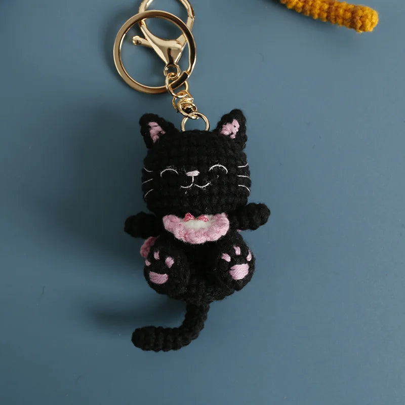 A handcrafted crochet black cat pendant keychain with a gold-colored ring attached.