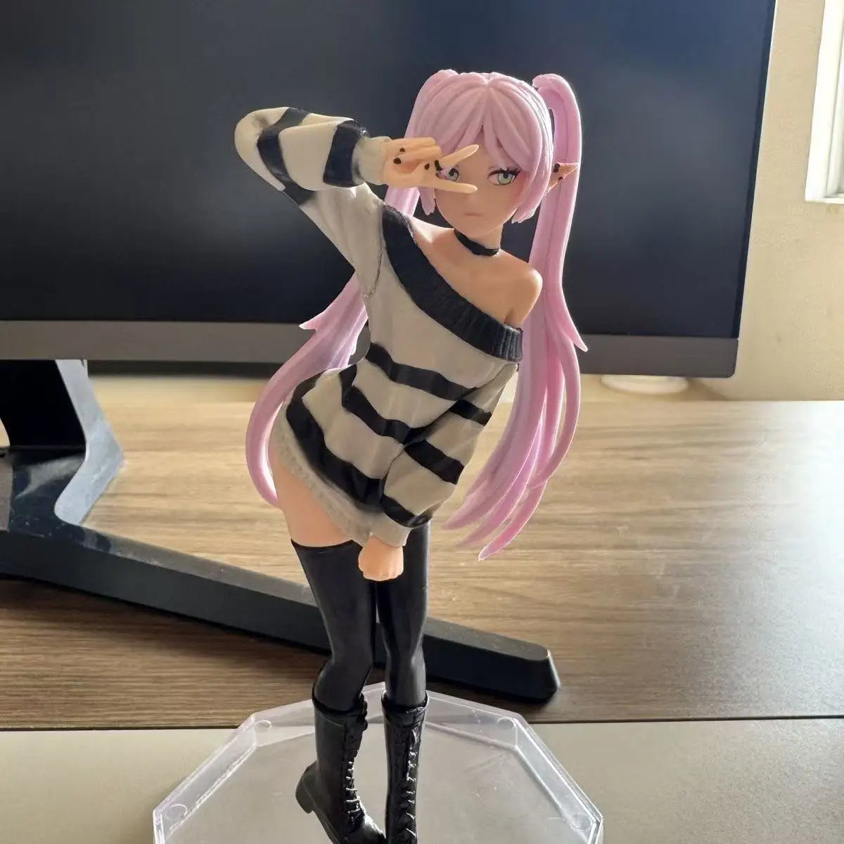 A figurine of an anime-style girl with pink hair wearing a striped sweater and black boots.