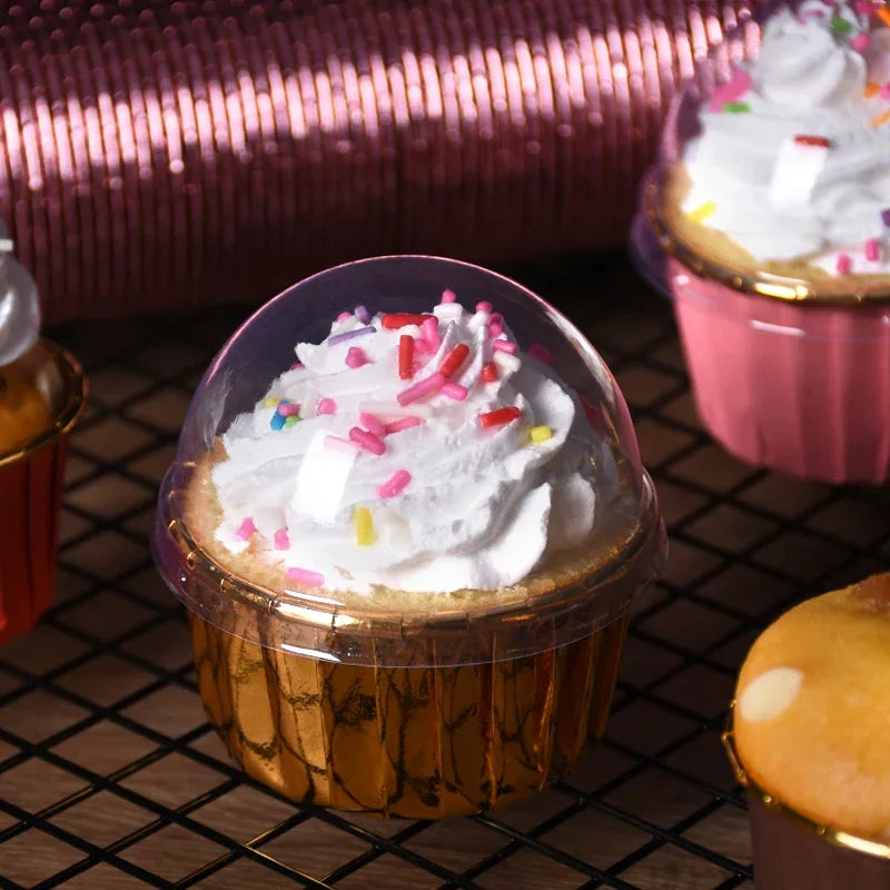 A close-up of a cupcake in a golden greaseproof liner filled with white frosting and colorful sprinkles.