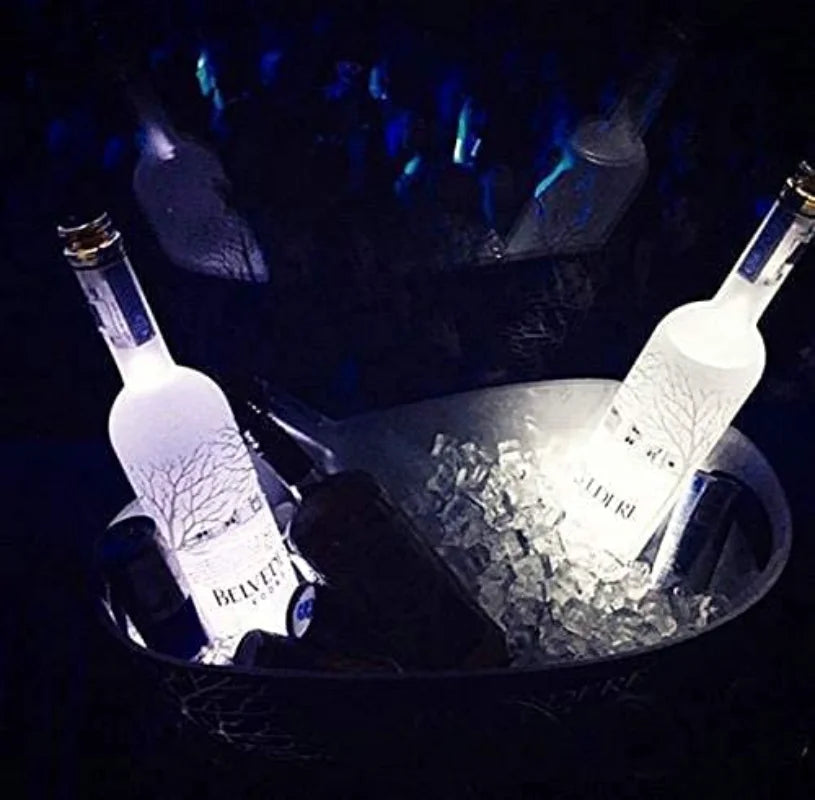 Two bottles are illuminated by luminous LED lights inside an ice bowl.