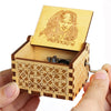 A carved wooden music box with a lid featuring a face design is held in a hand.