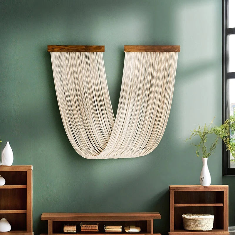 Boho macrame wall tapestry featuring light beige cord hanging on a teal green wall above wooden shelves.