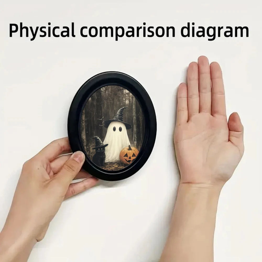 A hand holds a circular frame displaying vintage Halloween ghost and black cat wall art.