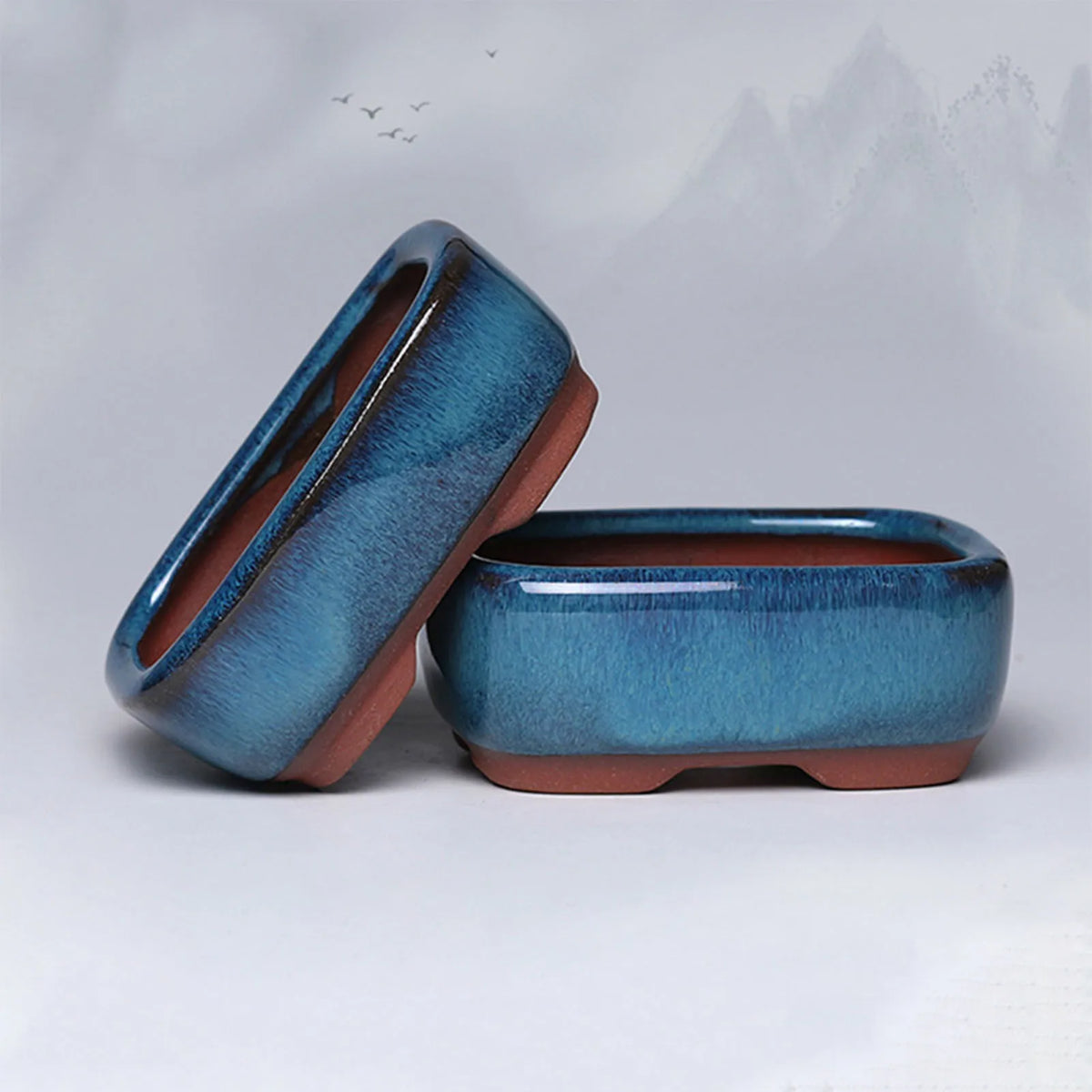 A blue ceramic succulent planter with a drainage hole shown from the side against a light gray background.