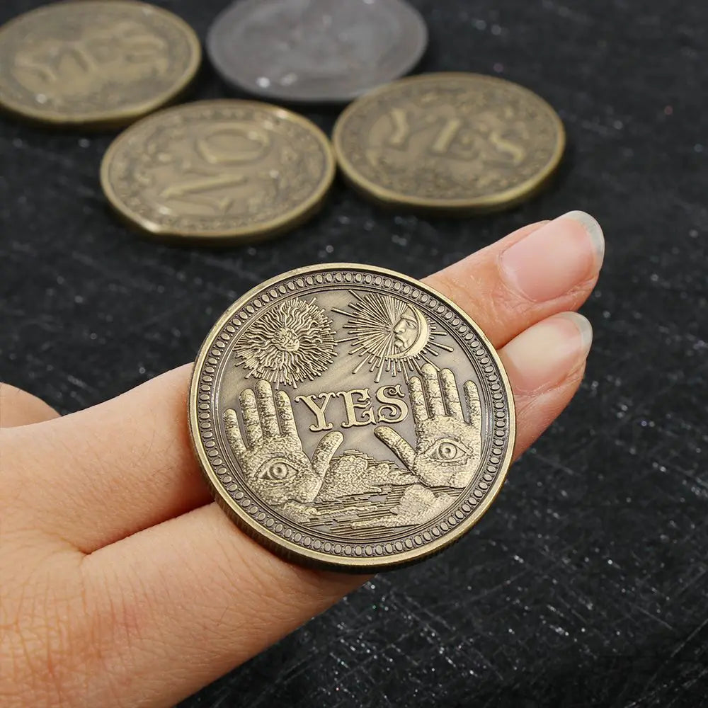 Una mano sostiene una moneda metálica conmemorativa dorada que presenta un ojo estilizado y la palabra SÍ.