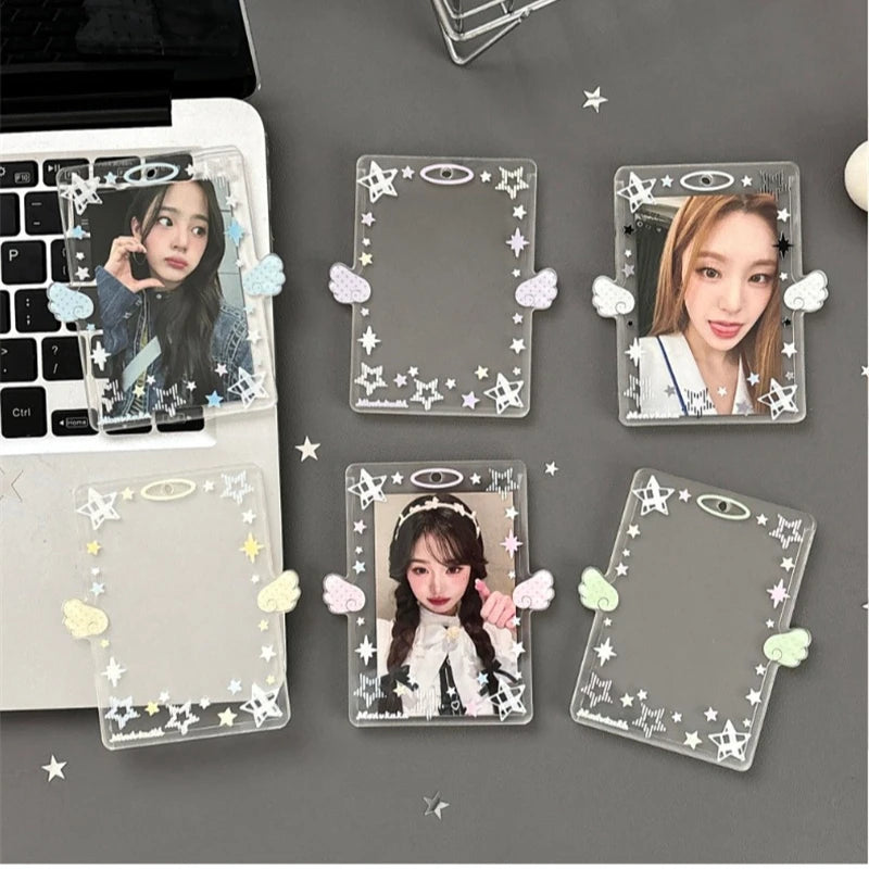 Clear acrylic photocard holders featuring stars and angel wings, displayed on a gray background.