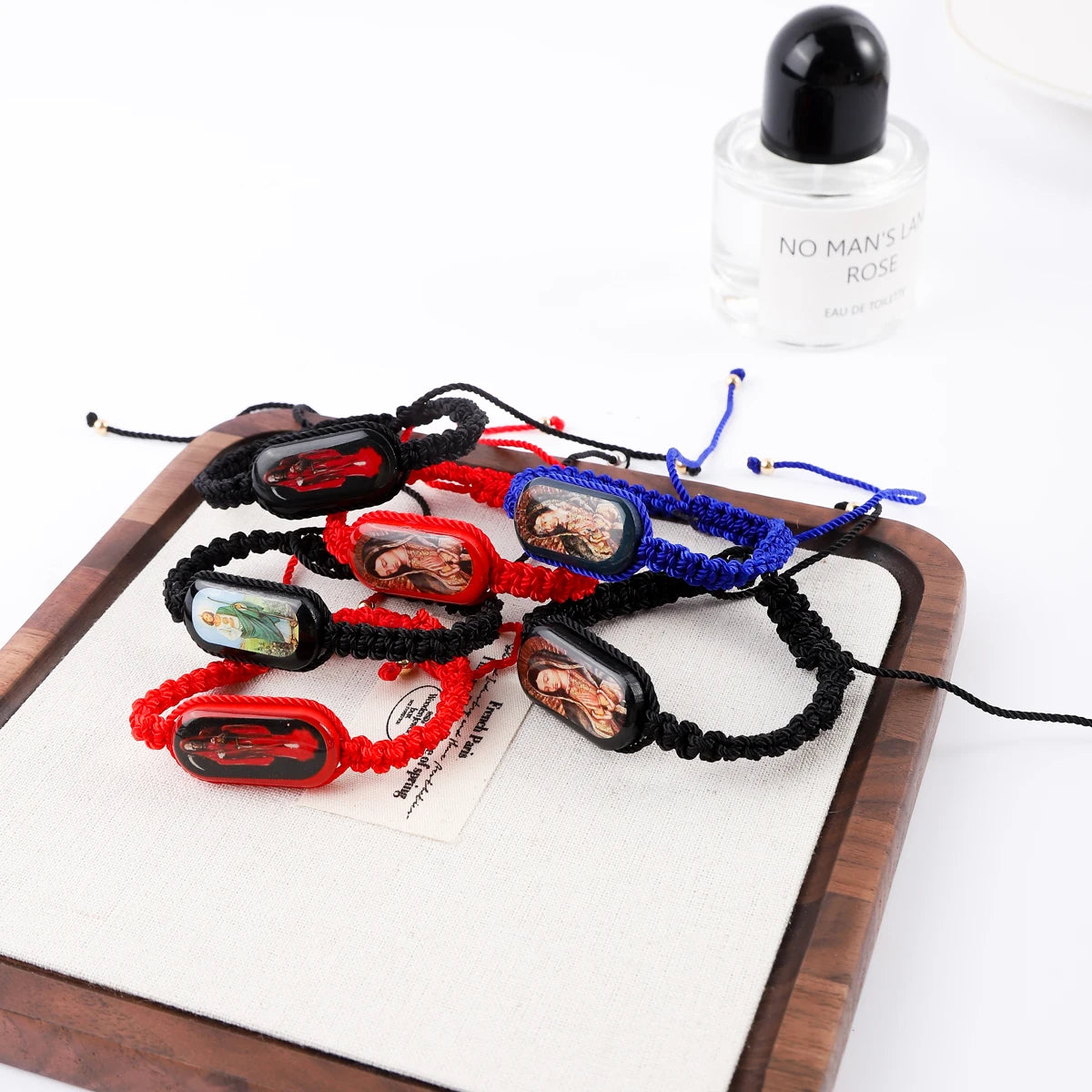 A collection of vintage wooden Virgin Mary prayer bracelets in various colors and materials displayed on a wooden board.
