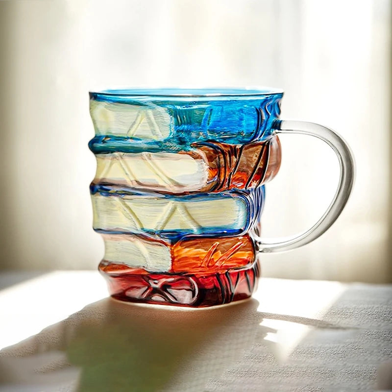 Hand-painted book design mug with layered blue, orange, and pink glass sections.