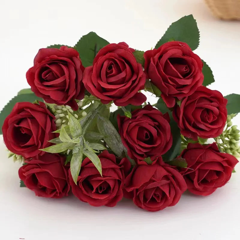 A bouquet of deep red artificial roses with green leaves for wedding and decoration.