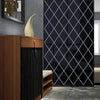 A dark diamond patterned mirror wall sticker displayed next to a wooden cabinet and a beige sculpture.