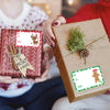 A person is holding a brown gift box tied with twine and green foliage, alongside a red gift box decorated with Christmas tag