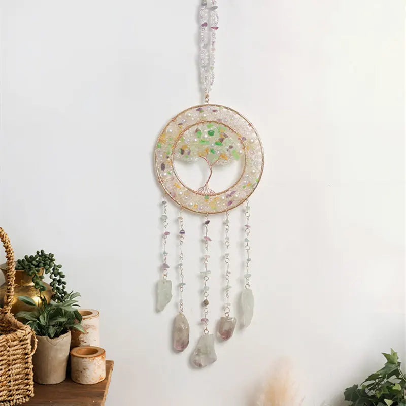 A hanging crystal tree of life sun catcher wall decor with a circular frame and dangling crystals.