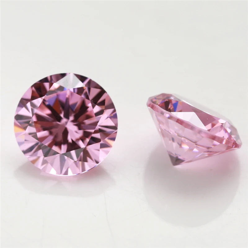 A close-up of a round cut pink gemstone and a triangular pink gemstone on a white surface.