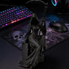 A black gothic female grim reaper figurine holding a scythe, displayed on a dark desk next to a gaming mouse and keyboard.