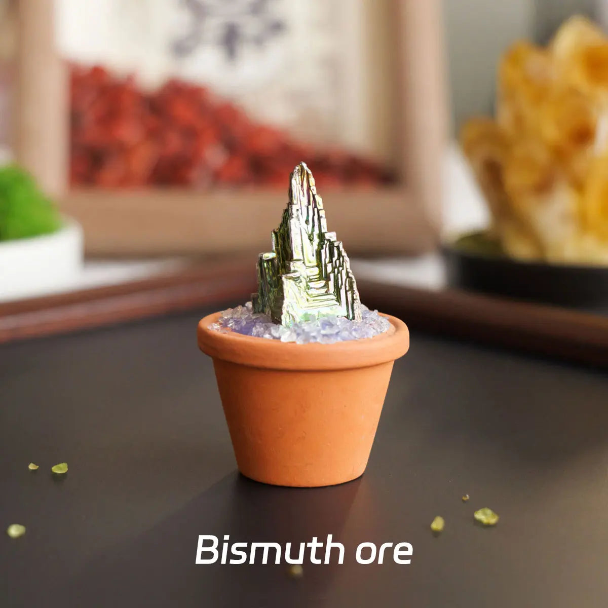 A small terracotta pot holds a miniature bismuth ore crystal structure on top, displayed on a dark surface.