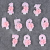 A set of glitter number cake candles from 1 to 9, each featuring a pink bow, displayed on a gray surface.