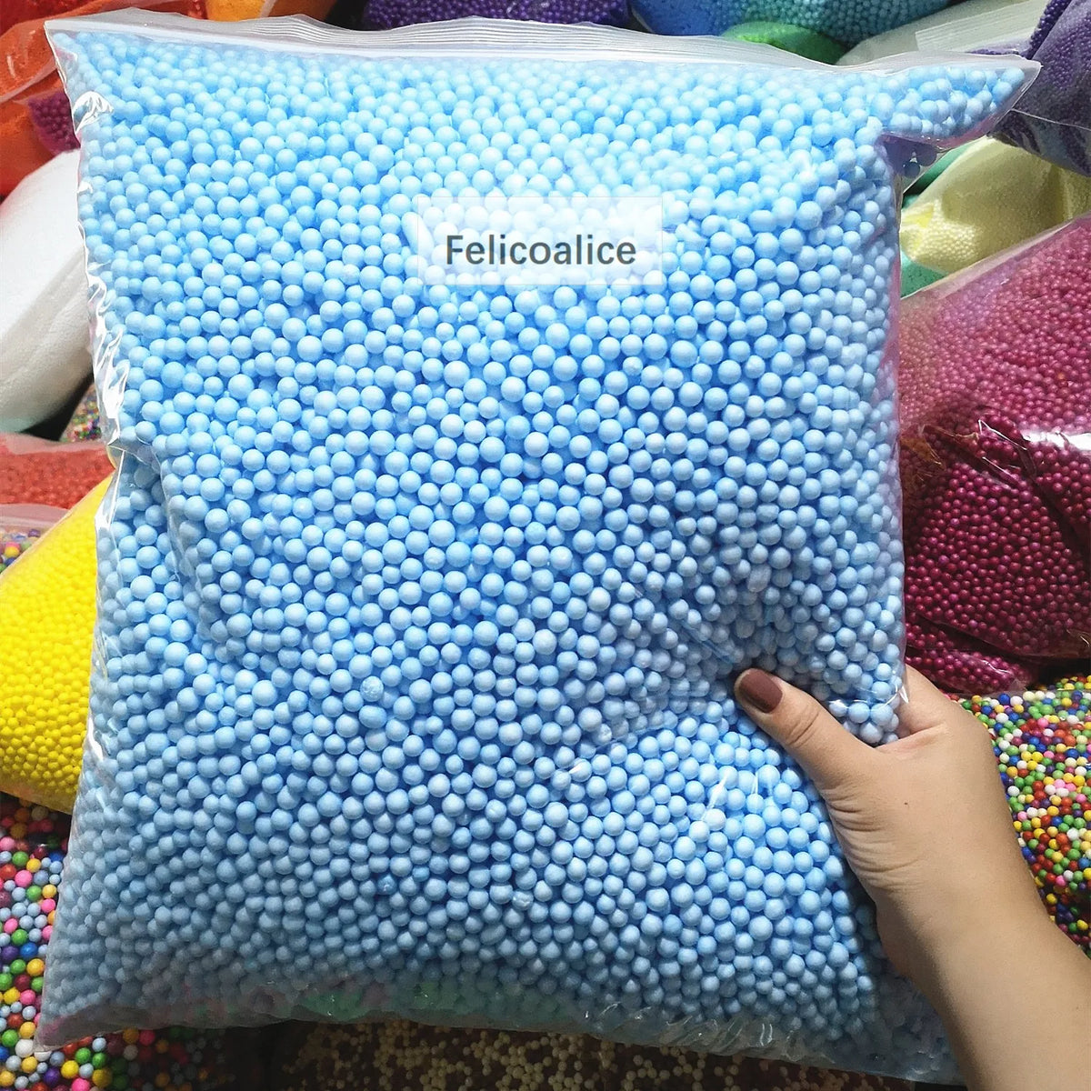 A clear bag filled with light blue foam beads labeled Felicoalice