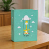 A teal album cover featuring a yellow giraffe in a hot air balloon design with stars and clouds.