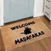 A rectangular, tan doormat with black text that reads WELCOME MADAFAKAS and features a silhouette of a cat with a knife.