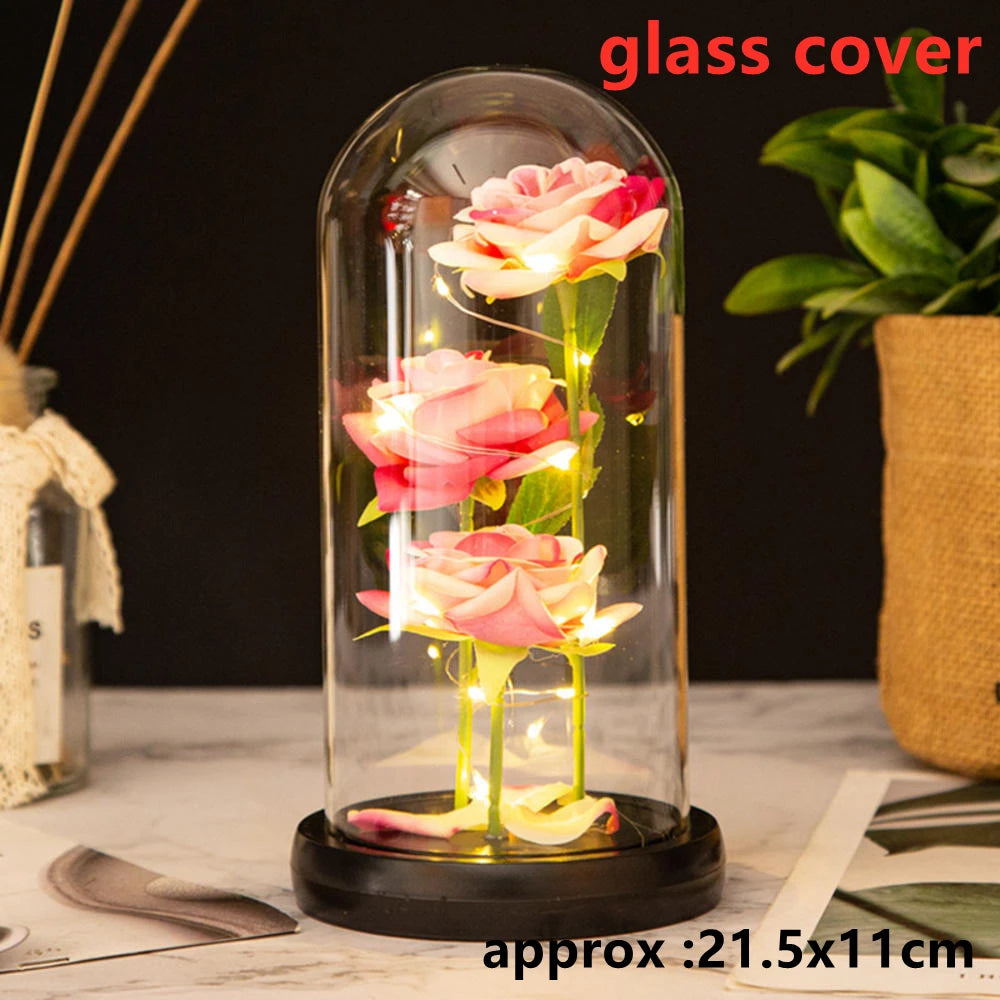 An LED galaxy rose artificial flower displayed inside a glass dome on a dark surface.
