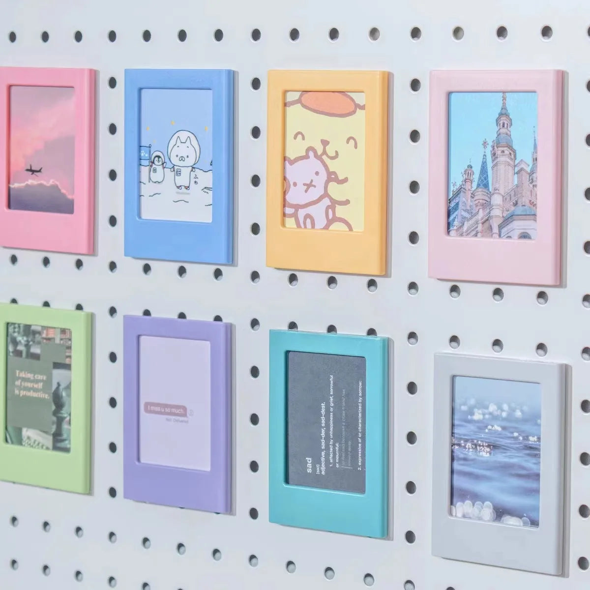 A collection of nine colorful magnetic photo frames in various pastel shades mounted on a white pegboard.