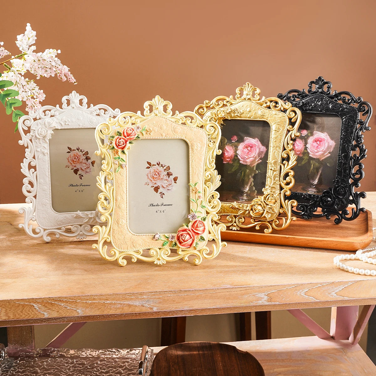 Three ornate gold and black resin photo frames with floral details displayed on a wooden surface.
