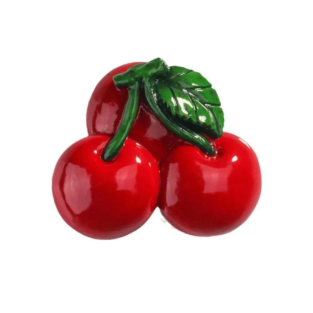A cluster of bright red cherry-like fruit with a green leaf, used as a fridge magnet.