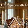 Multiple LED taper candle lights for decoration on a table with a Christmas tree in the background