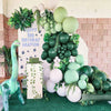 A vibrant party decoration featuring a giraffe statue and a large arrangement of green and light green latex balloons.