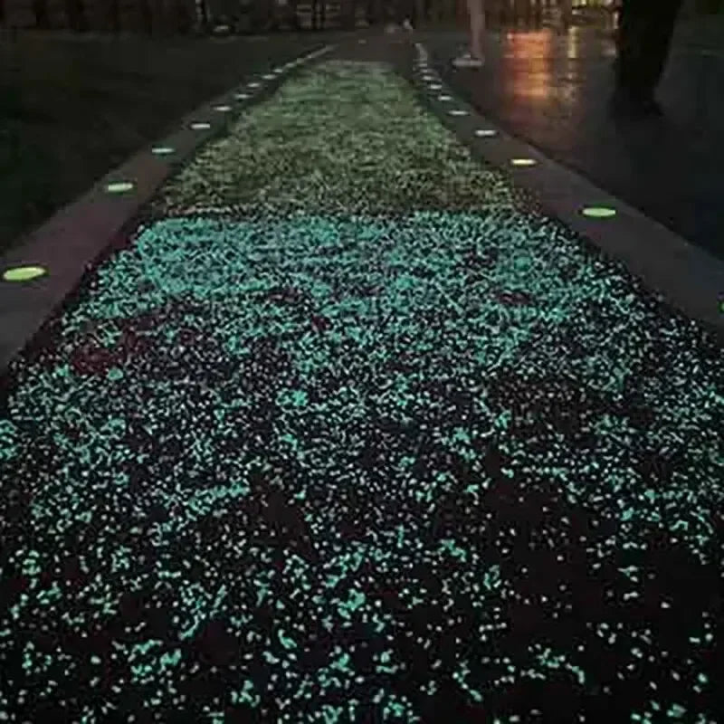 A pathway lined with glow-in-the-dark luminous pebbles illuminating a dark ground.