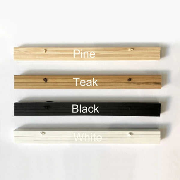 A display of four magnetic wooden art frames in Pine, Teak, Black, and White.