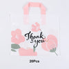 A white gift bag with pink floral designs and pink ribbon handles.