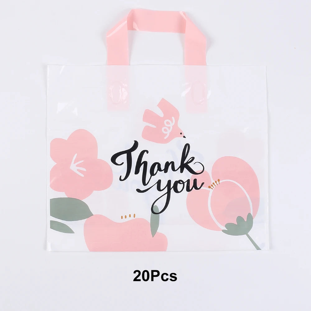 A white gift bag with pink floral designs and pink ribbon handles.