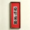 A vertical wooden frame with a red background displaying a series of small photos.
