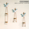 Three decorative glass terrariums featuring white and blue seagull-like flowers hanging by twine.