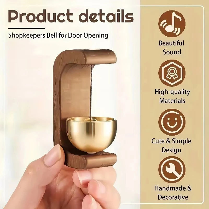 A hand holds a wooden doorbell for door opening, featuring a brass bell and a simple design.