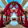Una gran instalación de evento con un arco grande cubierto con tela magenta transparente y arreglos florales.