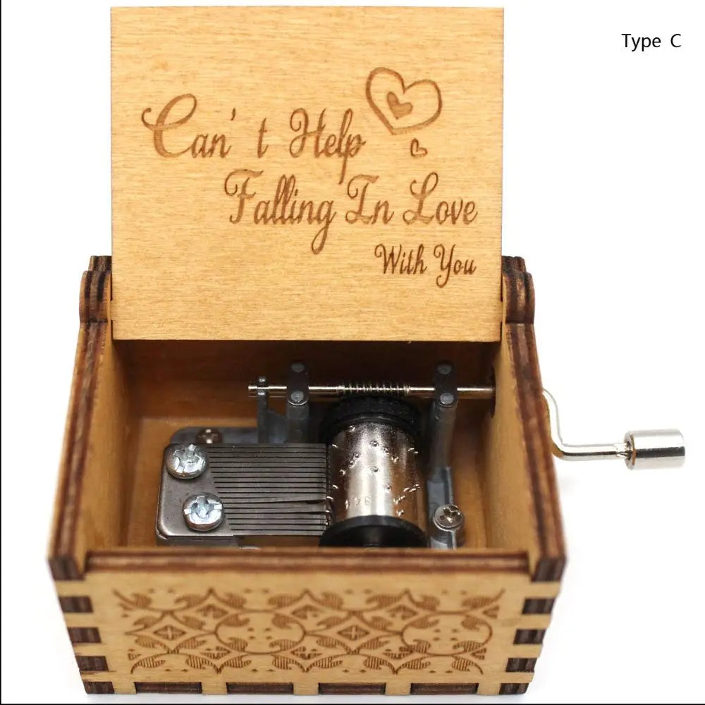 A vintage hand-cranked wooden music box with a lid engraved 'Can't Help Falling In Love With You' and a visible winding mecha