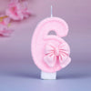 Glittery pink number six birthday candle with a decorative pink bow