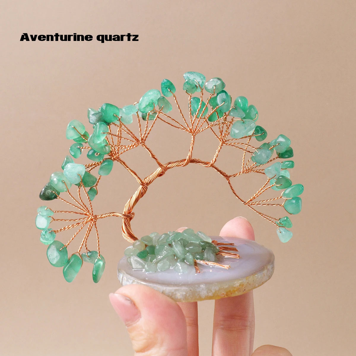 A branch-like Aventurine quartz crystal tree made of green beads mounted on a gold wire structure resting on a light-colored 